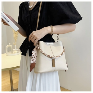 Detail of minimalist cream bucket bag with floral scarf and gold chain strap