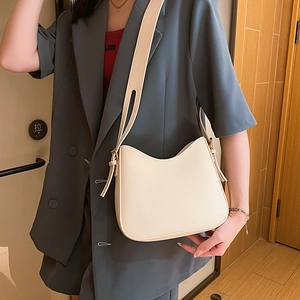 Minimalist creamy white leather crescent shoulder bag with tassel detail on model