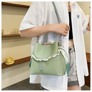 Detail of light green bucket bag with floral scarf handle and gold metallic hardware