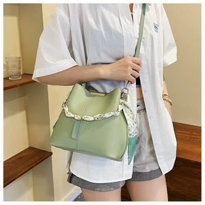 Detail of light green bucket bag with a decorative silk scarf wrapped around a gold chain