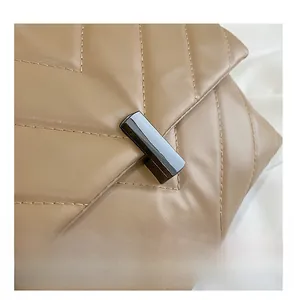 Detail of khaki leather handbag with V-shaped quilting and sleek black metal turn-lock