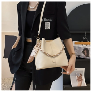 Detail of cream bucket bag with leopard scarf handle and thin shoulder strap on model