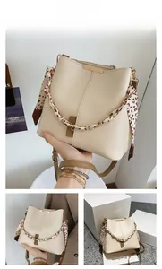 Detail of cream bucket bag with brown leather base and leopard print silk scarf chain