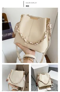 Detail showing cream bucket bag with leopard print scarf chain handle and long shoulder strap