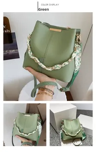 Detail of green leather bucket bag featuring silk scarf wrapped chain handle and gold hardware