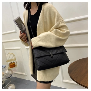 Detail of black quilted leather shoulder bag with metallic clasp on a stylish model
