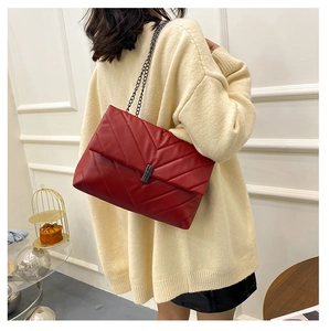 Close-up of red quilted leather shoulder bag with dark nickel metal chain and clasp
