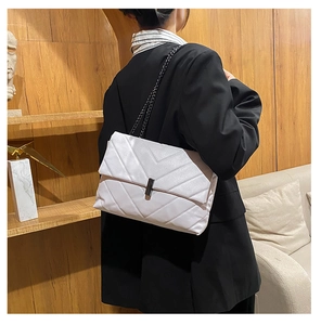 Detail view of quilted white chain bag worn with a black blazer in a luxury setting