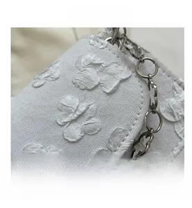 Detailed close-up of white floral relief texture and flower-shaped silver chain strap