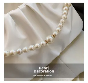 Détail du sac à bandoulière blanc plissé avec chaîne de perles et strass dorés brillants