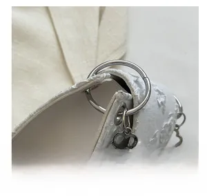Detailed shot of white floral embroidery fabric and reinforced silver metal hardware loop