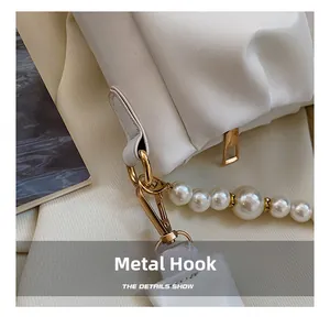 Détail du sac en cuir plissé blanc avec bandoulière en perles et crochets dorés