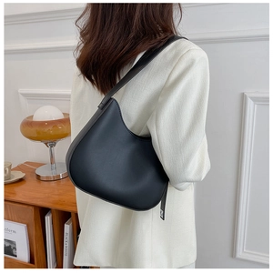 Close-up of black matte leather saddle bag styled with a professional white suit