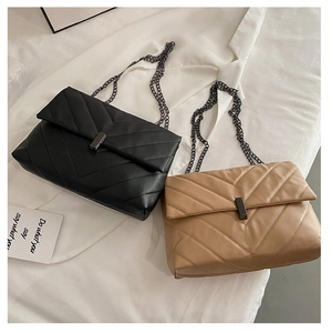 Detail of quilted crossbody bags in black and khaki with V-shaped stitching and chain straps