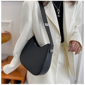 Close-up of black matte saddle bag with adjustable strap and silver buckle on model