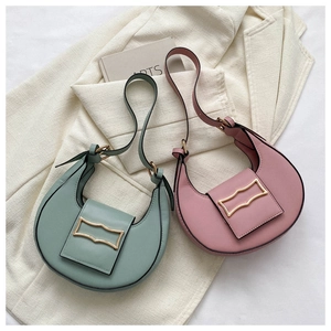 Detail view of stylish crescent underarm shoulder bags in green and pink with metal buckles.