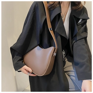 Brown leather hobo bag with adjustable strap and silver buckle on a black coat
