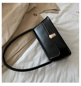 Detail of classic black leather baguette bag with a sleek gold rectangular metal clasp