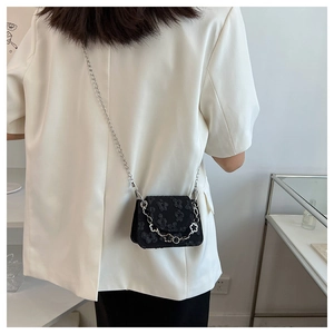 Detail of black jacquard mini round bag with 3D floral texture and silver chain strap