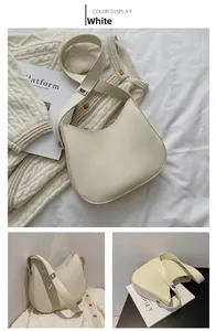 Detail view of a cream-white crescent shoulder bag with wide strap and silver buckle