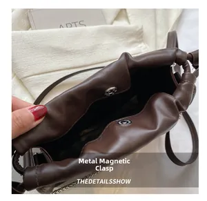 Dettaglio della chiusura magnetica sicura su una borsa a tracolla in pelle marrone.