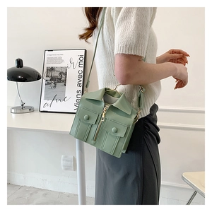 Detail of jacket-shaped crossbody bag in sage green with zippers and pockets
