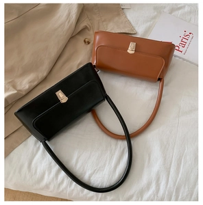Detail of elegant black and caramel baguette bags with golden buckles on a chic French background