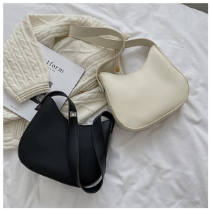 Minimalist cream and black half-moon shoulder bags with silver buckles on white bedding