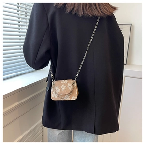 Mini jacquard crossbody bag with floral pattern and chain strap on a female model