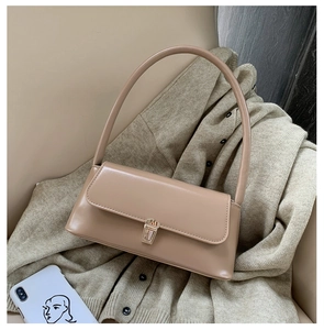 Close-up of khaki leather baguette bag with gold metal buckle on grey knitwear