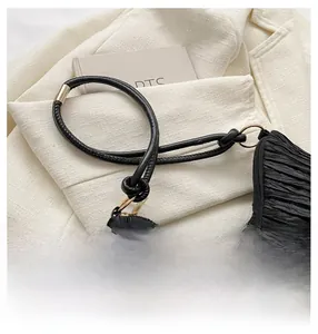Close-up van een zwarte geplooide corduroy hobo-tas met goudkleurige metalen ringen