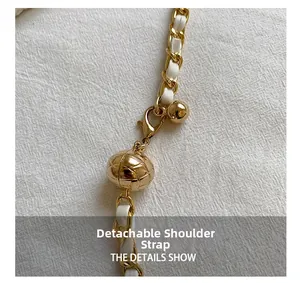 Detail of white chain strap with gold metal adjustment ball and lobster clasp