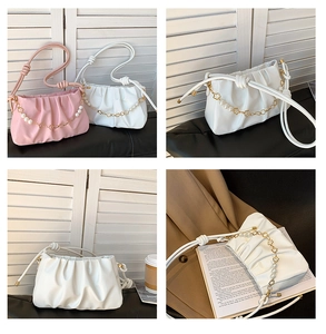 Detail of ruched cloud bag with decorative pearl and gold flower chain strap accents