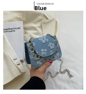 Detail of light blue jacquard fabric purse with floral patterns and silver chain strap