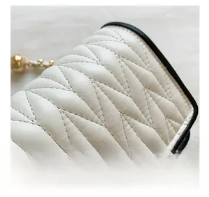 Close-up of white quilted leather bag with V-shaped stitching and golden twist lock