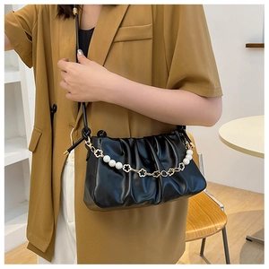 Detail of black pleated cloud bag featuring elegant pearl and gold flower chain strap