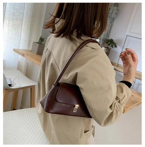 Detail of vintage burgundy leather baguette bag with elegant gold metal clasp closure