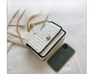 Mini crossbody bag with V-shaped quilting and metal lock next to a smartphone for size