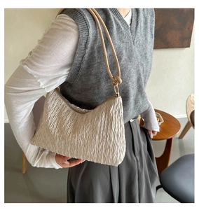 Detail of beige corduroy shoulder bag showing pleated texture and slender handle