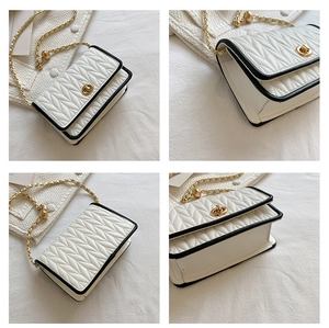 Detail view of white quilted crossbody bag with black piping and gold chain strap