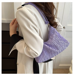Detailopname van de lila geplooide tas met goudkleurige ring en knoop schouderband