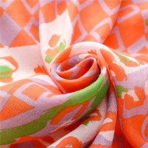 Macro detail of soft cotton-linen scarf showing orange and green geometric diamond texture