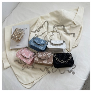 Detail of jacquard fabric mini bag with floral patterns and a metal chain strap decoration