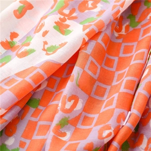 Detail of soft thick scarf featuring vibrant orange and green geometric diamond patterns