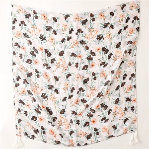 Détail d'une écharpe longue blanche avec motif floral et glands à franges décoratives