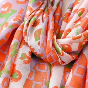 Macro shot of abstract orange and green geometric print on soft thick cotton scarf fabric