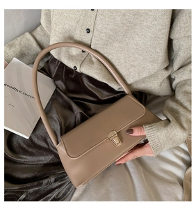 Detail of khaki baguette shoulder bag with gold square buckle on a model in beige knitwear