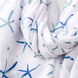 Detail of soft cotton-linen scarf with blue starfish print and delicate fringe texture