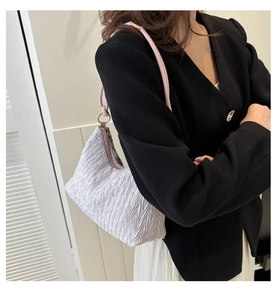 Silver pleated shoulder bag with pink straps worn over a black blazer for women