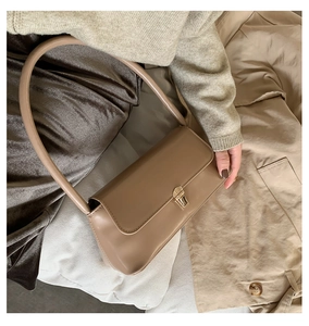 Detail of beige baguette bag with gold buckle on trench coat background